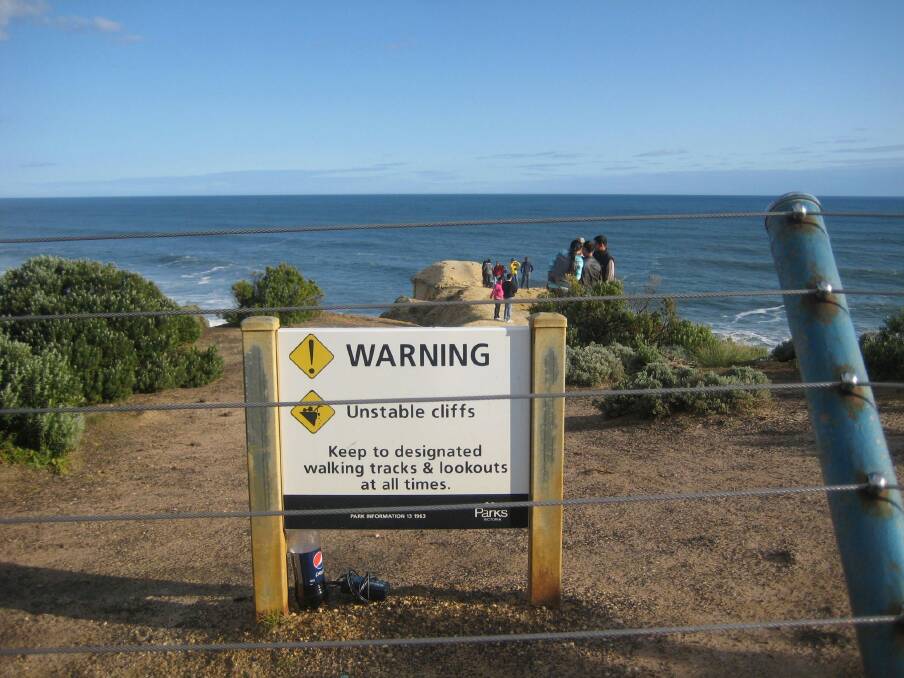 Tourists at Victoria's Twelve Apostles ignore a fence and sign to gain a better view. Photo: Ian Rees