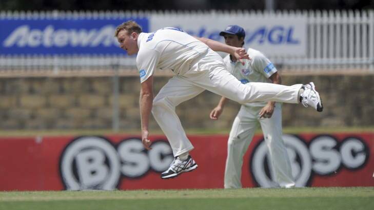 NSW bowler Doug Bollinger bends his back during the Sheffield Shield clash with Queensland at Manuka Oval. Photo: Graham Tidy