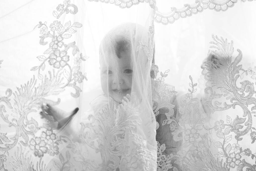 Cheeky William Andrew peers out from under mum's Martina Liana dress. The Canberra Times, Wednesday 26 October 2016 Photo: LIGHTBULBSTUDIO