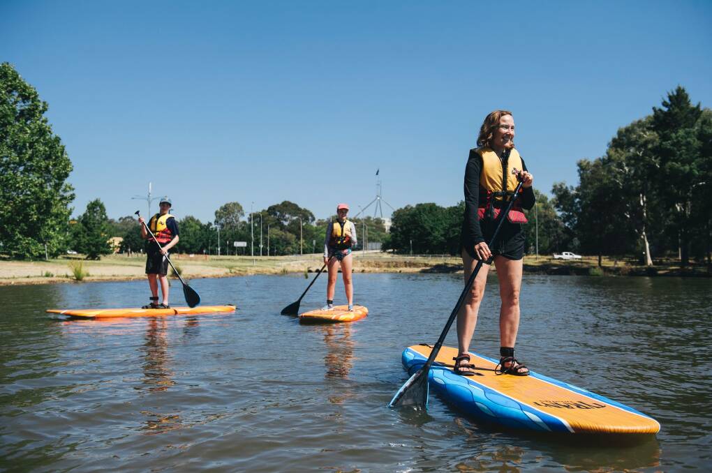 Angela Frimberger with her children Ivy and Alex Moore from Port Maquarie stand up paddle boarding on Lake Burley Griffin on Sunday afternoon. Photo: Rohan Thomson