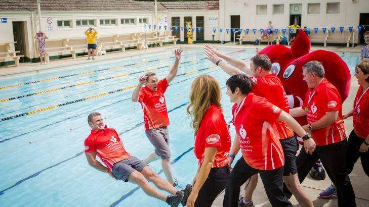 Top finish: Eleven Canberrans who took part in the Heart Foundation's 12-week Canberra Celebrity Heart challenge push personal trainer Lee Campbell and Heart Foundation ACT CEO Tony Stubbs into a pool to celebrate the end of the challenge. Photo: Jamila Toderas