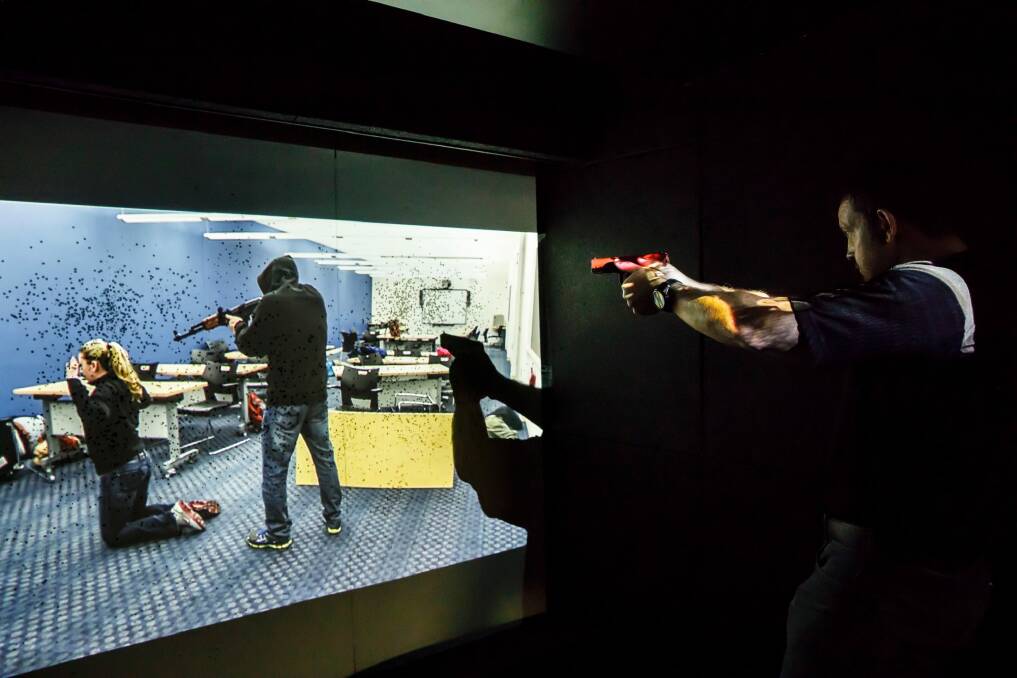 Paul Burns demonstrates the company's prototype mobile firing range, where police and soldiers must react to virtual scenarios.  Photo: Sitthixay Ditthavong