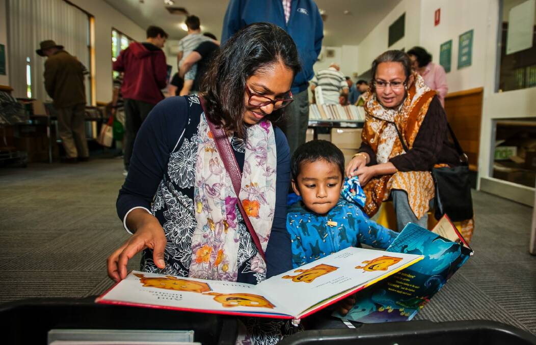 Tazeen Taj with her son Aaqil Ansary, 2, looking through children's books at Tuggeranong Library as part of the ACT's first library sale. Photo: Elesa Kurtz