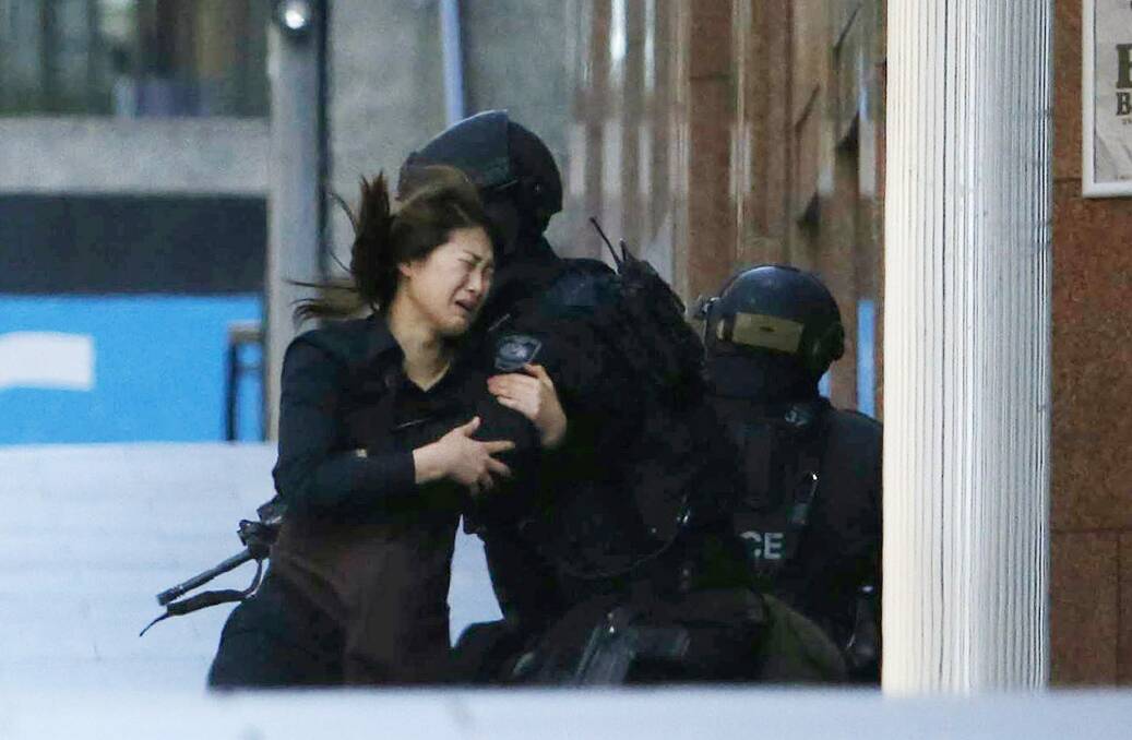 A hostage runs to police after fleeing Sydney's Lindt cafe on December 15, 2014. Photo: Jason Reed