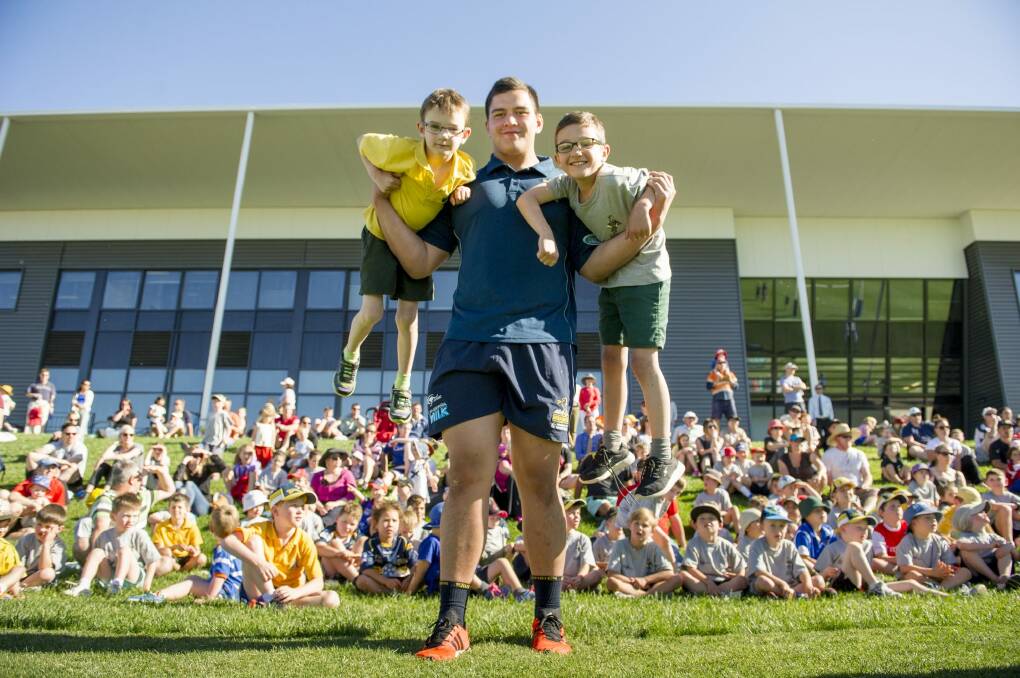 Brumbies giant Tyrel Lomax lifts up Lachlan, 7, and Nicolas, 8, at the Budding Brumbies school clinics. Photo: Jay Cronan