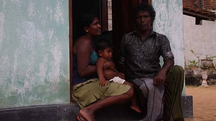 Christopher Fernando sits on the step at his single-room home in Negombo, on Sri Lanka's west coast, with his daughter-in-law Aruni and grandson Shehan. Photo: Ben Doherty