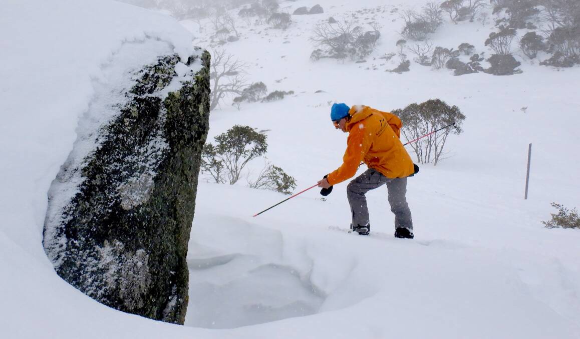 As the blizzard sets in, Peter Cocker uses an avalanche probe to check the best spot to dig a snow cave. Photo: Tim the Yowie Man