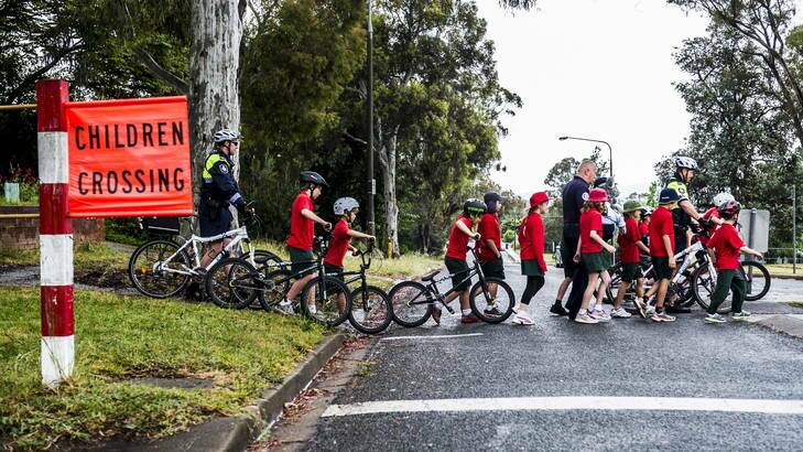 Police teach Macquarie Primary School students about road awareness outside the school yesterday. Photo: Rohan Thomson