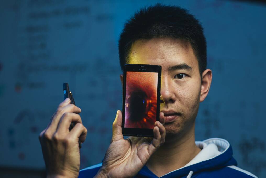 Kenny Cen using a lens on his phone created with "lens maker", a cheap way of making small lenses.  Photo: Rohan Thomson