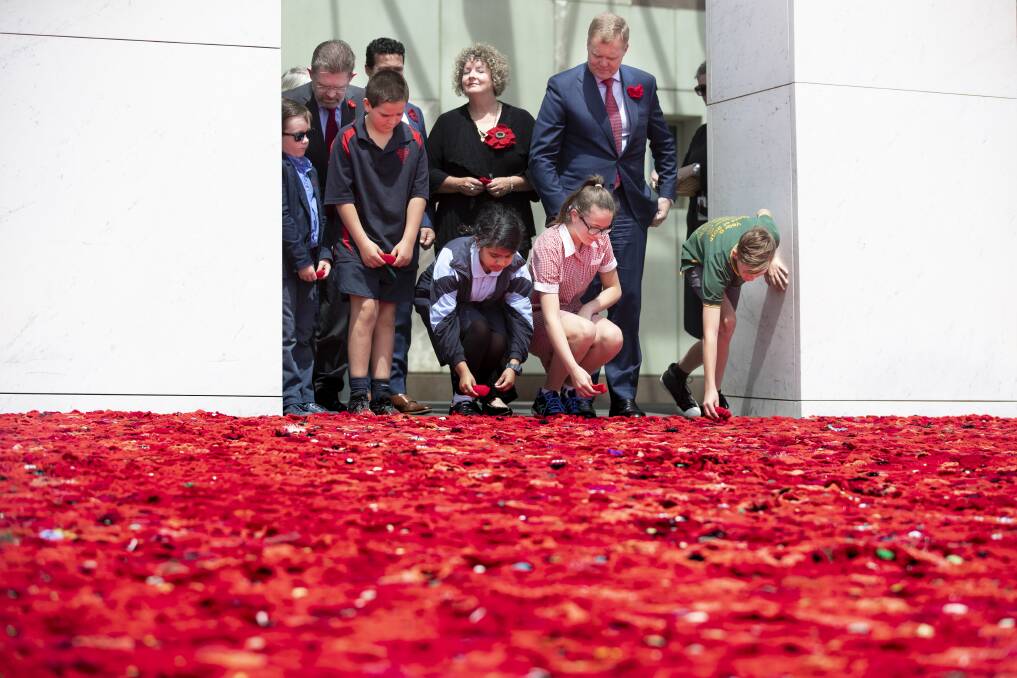 Senator Scott Ryan's son Nick Ryan, Aiden Makem, 10, from Tarcutta Public, Aysha Sajid, 11, from The Grange school in Minto, Annabell Wakefield, 12, from Uranquinty Public near Wagga, and Clay Barton, 11, from Kapooka Public add poppies to the poppy display in the Parliament House forecourt on Friday Photo: Sitthixay Ditthavong