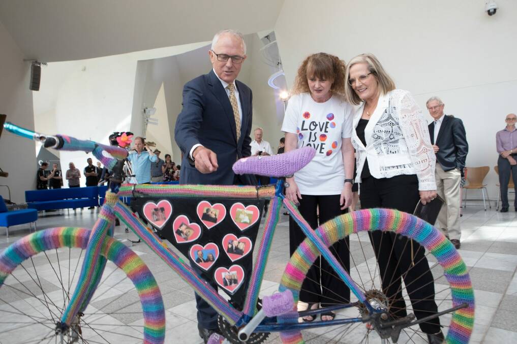 Prime Minister Malcolm Turnbull with the crocheted Love Wheels bike, its artist Eloise Murphy and his wife Lucy at the National Museum of Australia on Thursday. The bike is adorned with pictures of the Turnbulls, celebrating their almost 38-year marriage, as well as the successful YES campaign in the marriage equality vote. Photo: NATIONAL MUSEUM OF AUSTRALIA