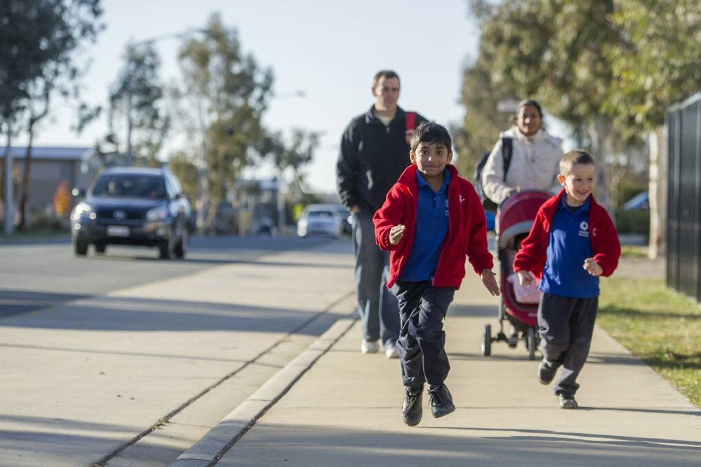 Harrison School students (front) Avyukth Sudharsan, 6, and Levi Stoddart, 5, with parents (rear) Michael Stoddart and Sunitha Sampath. Parking delays have been a key problem for many of the ACT's schools but parents' want more than extra fines.  Photo: Jay Cronan