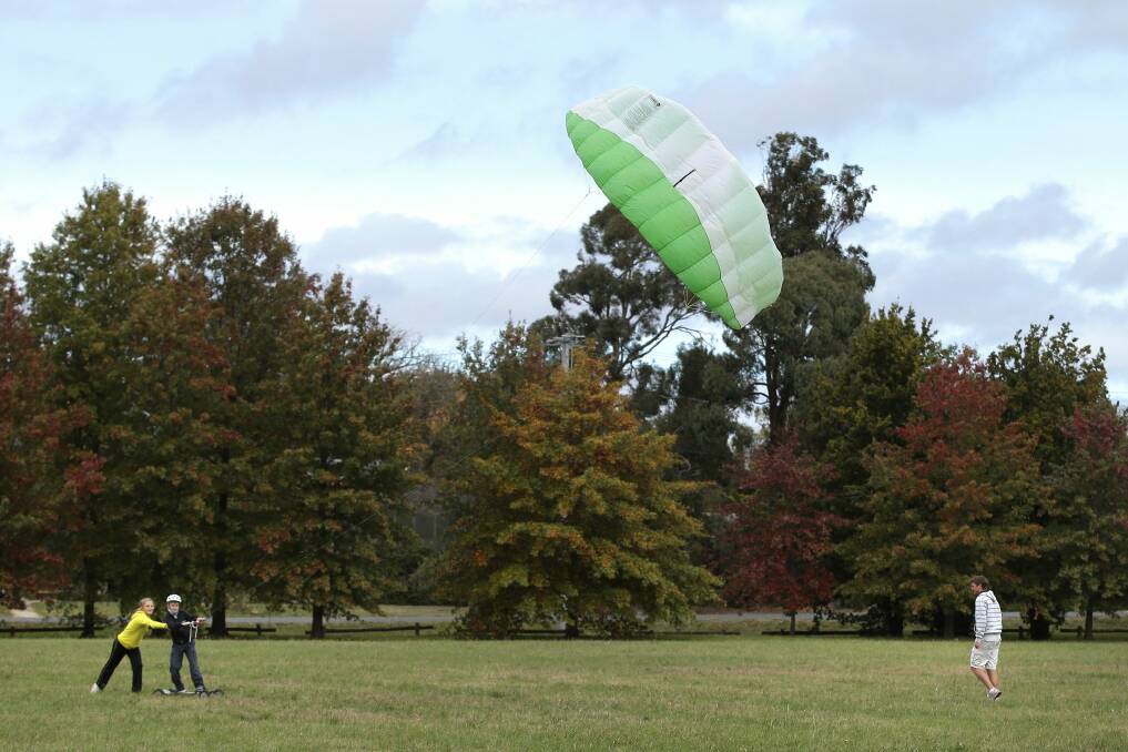 Elise Campbell, 14, helps brother Evan Campbell, 12, get his kite in the air as Braden Campbell, 15, looks on near their home in Yarralumla on Monday Photo: Jeffrey Chan