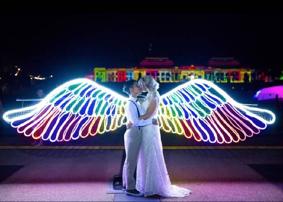 Mhera Nelson-Insch and Bella Insch snuck out of their wedding at the NGA to grab a memorable photo at the Neon Angel Wings installation at Enlighten. Photo: Supplied