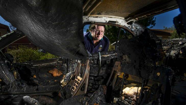Ray Whitehead's looks into the melted remains of the interior of his son's holden commodore that was firebombed Isabella Plains. Photo: Rohan Thomson