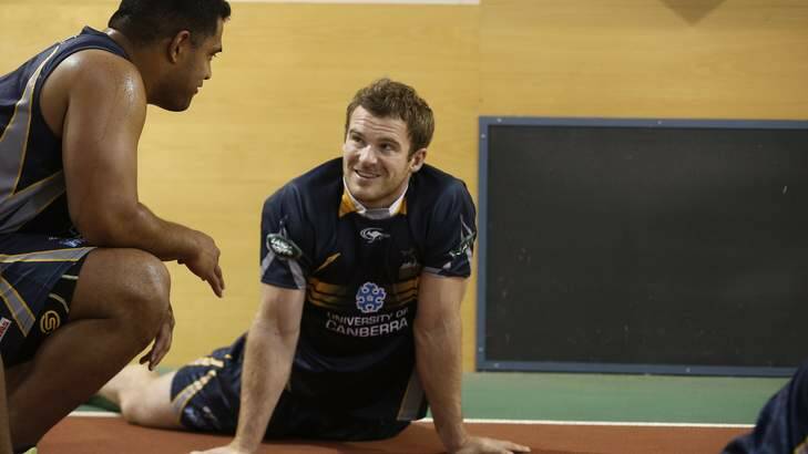 ACT Brumbies player Pat McCabe, centre, chats with a team mate as he warms up before biometric testing in the AIS Indoor Athletics Track. Photo: Jeffrey Chan