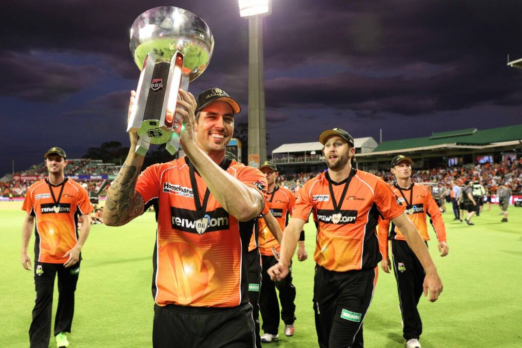 Reigning champs: Mitchell Johnson of the Scorchers carries the trophy after winning last season's BBL T20 final against the Sydney Sixers in January. Photo: Richard Wainwright