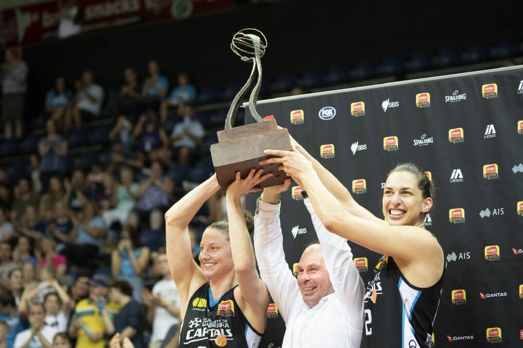 The Canberra Capitals' Kelsey Griffin, Paul Goriss, and Marianna Tolo hoist the WNBL championship trophy. Photo: Sitthixay Ditthavong