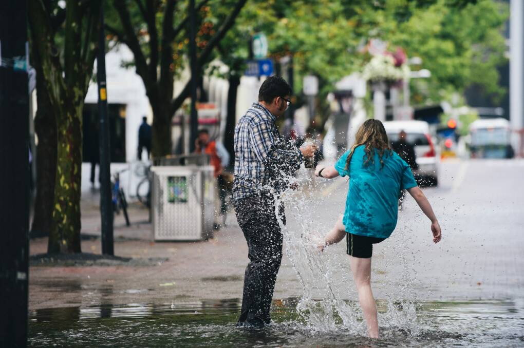Friends Jayden Goodrem, 18, of Paige, and Ashleigh Peet, 19, of Kambah enjoy a puddle in Garema Place. Photo: Rohan Thomson