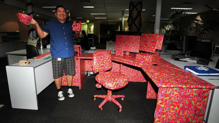 Canberra Times staffer Anderi Abdulhamid unwraps his Christmas prank - his entire workstation. Photo: Karleen Minney