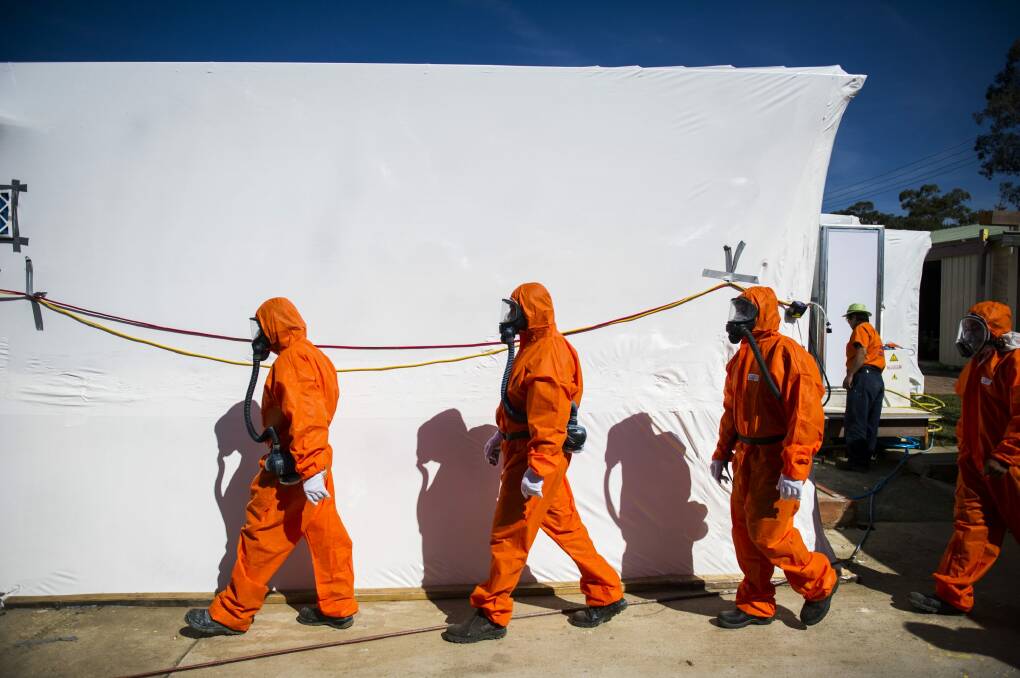 Workers leave the decontamination area of an asbestos house in Hiles Place, Kambah, that has been shrink wrapped in preparation for demolition. Photo: Rohan Thomson