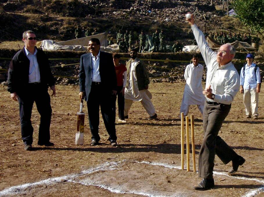 John Howard (right) bowls a cricket ball in Pakistan, and trips shortly afterwards. Photo: Asif Hassan