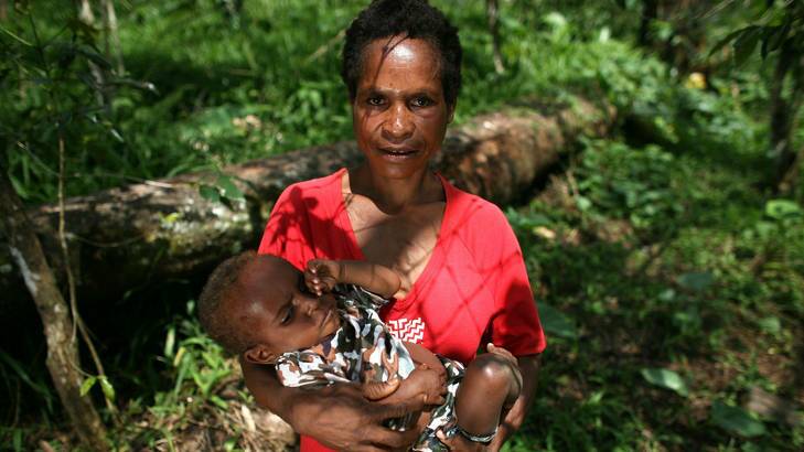 Mother-of-six, Wendy Daniell, with her one-year-old son, pictured next to the log she used to prop her legs up while giving birth in Papua New Guinea. Photo: Supplied