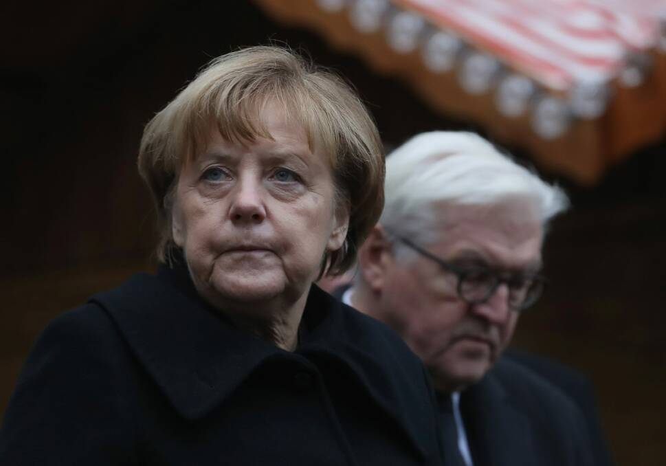 German Chancellor Angela Merkel and Foreign Minister Frank-Walter Steinmeier lay flowers at the Berlin Christmas market where 12 people died after a truck ploughed onto the crowd. Photo: Getty Images