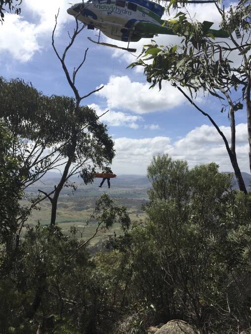The Snowyhydro helicopter lifts the injured bushwalker, and a paramedic, from Mount Tennent, Namadgi National Park.  Photo: Duncan Thomas