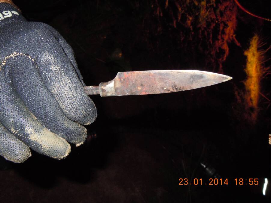 A diver holds a knife found in the dam. Photo: afp15786