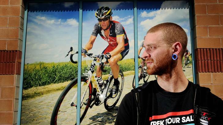 Jimmy Quinton, 23, who works at the Onya bike shop in Tuggeranong looks at a picture of Lance Armstrong that will soon be taken down. Photo: Colleen Petch