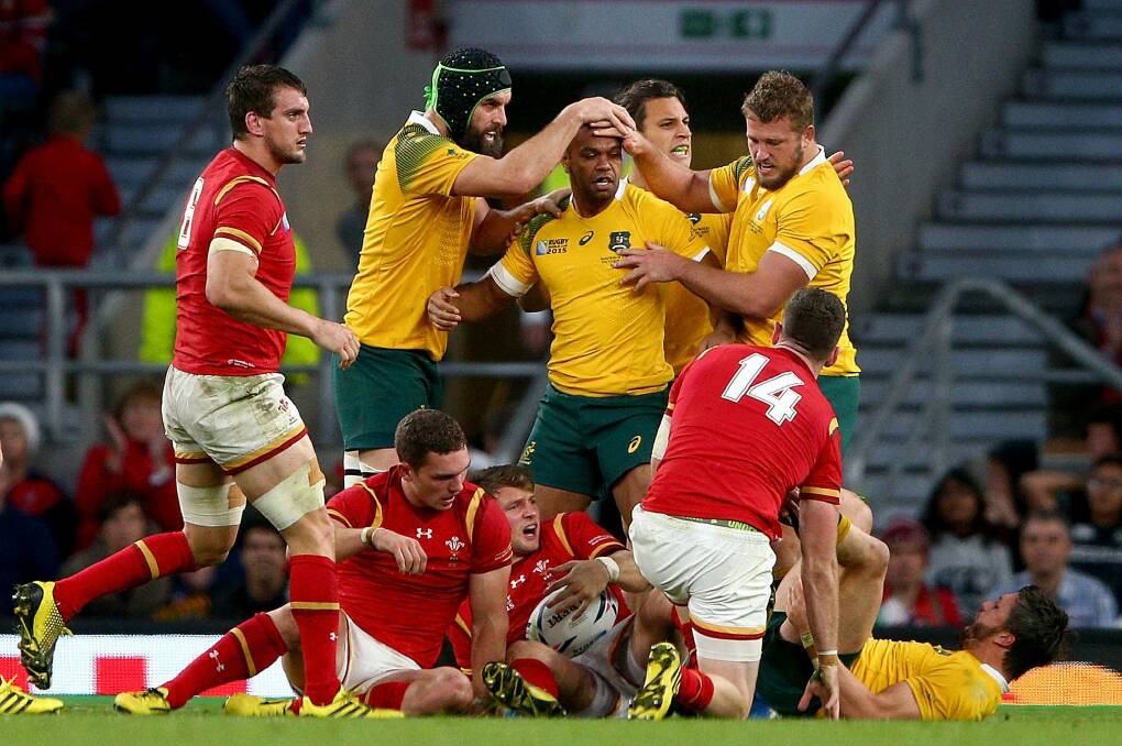 Tough times: Australian players celebrate after winning a penaty to relieve Welsh pressure on their tryline. Photo: Getty Images