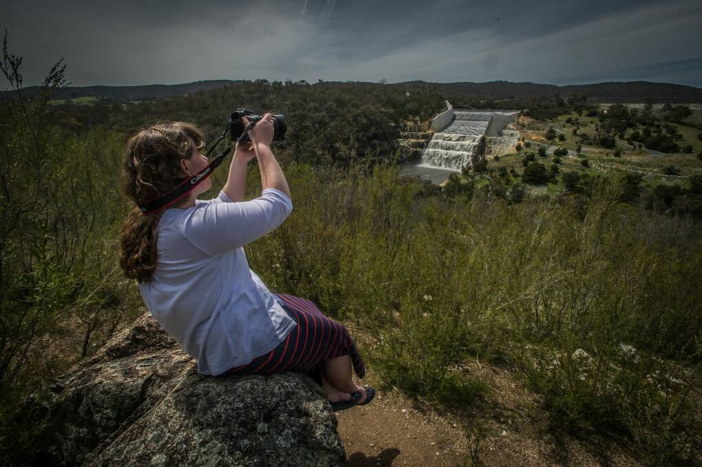 Photographer Bethany Roberts catches photos as Googong dam spills over the walls after recent rains.  Photo: Karleen Minney