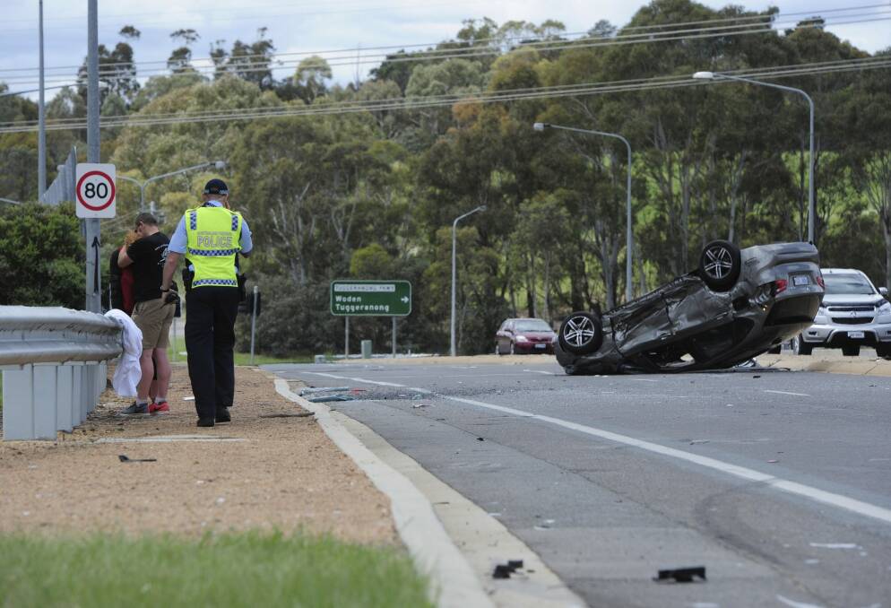 The vehicle on its roof on the Cotter Road overpass on the Tuggeranong Parkway.  Photo: Graham Tidy