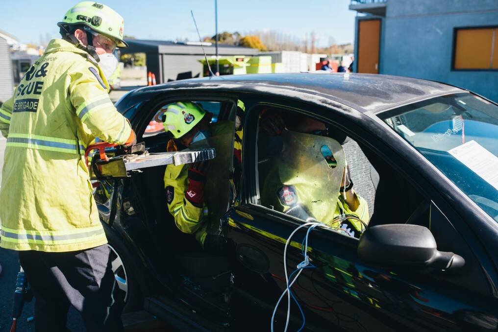 The firefighters using the jaws of life to pry apart the door frame of the abandoned Barina. Photo: Rohan Thomson