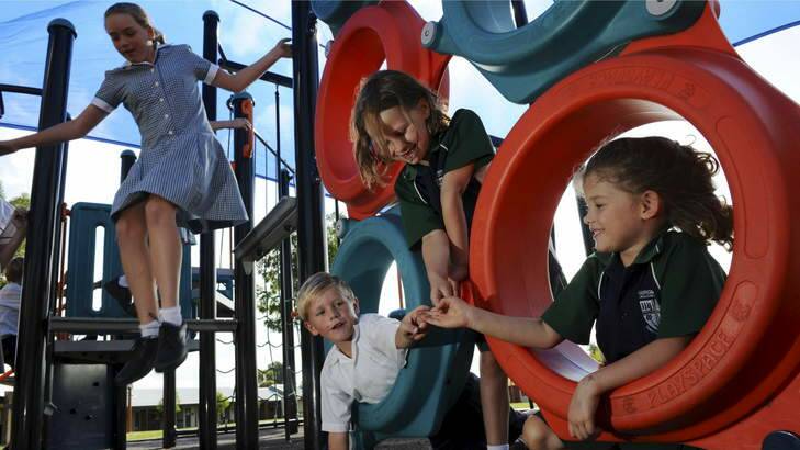 Burgmann Anglican students (foreground, from left) Lachlan Furini, Alison Riley and Kate Riley play on yard equipment after school. Photo: Graham Tidy