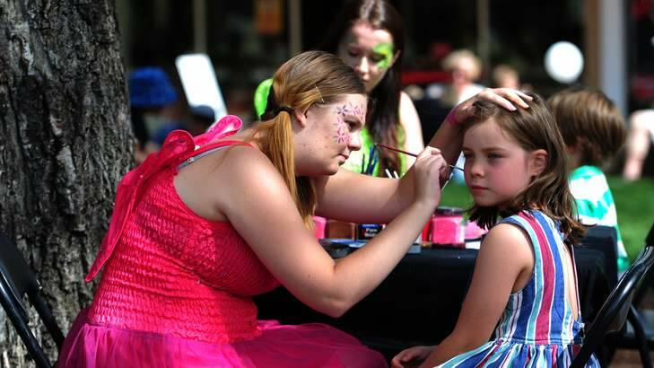 Madelyn Terata, 7, of Kingston, has her face painted by Natalie Porter, of Mawson, at Green Square, Kingston. Photo: Melissa Adams