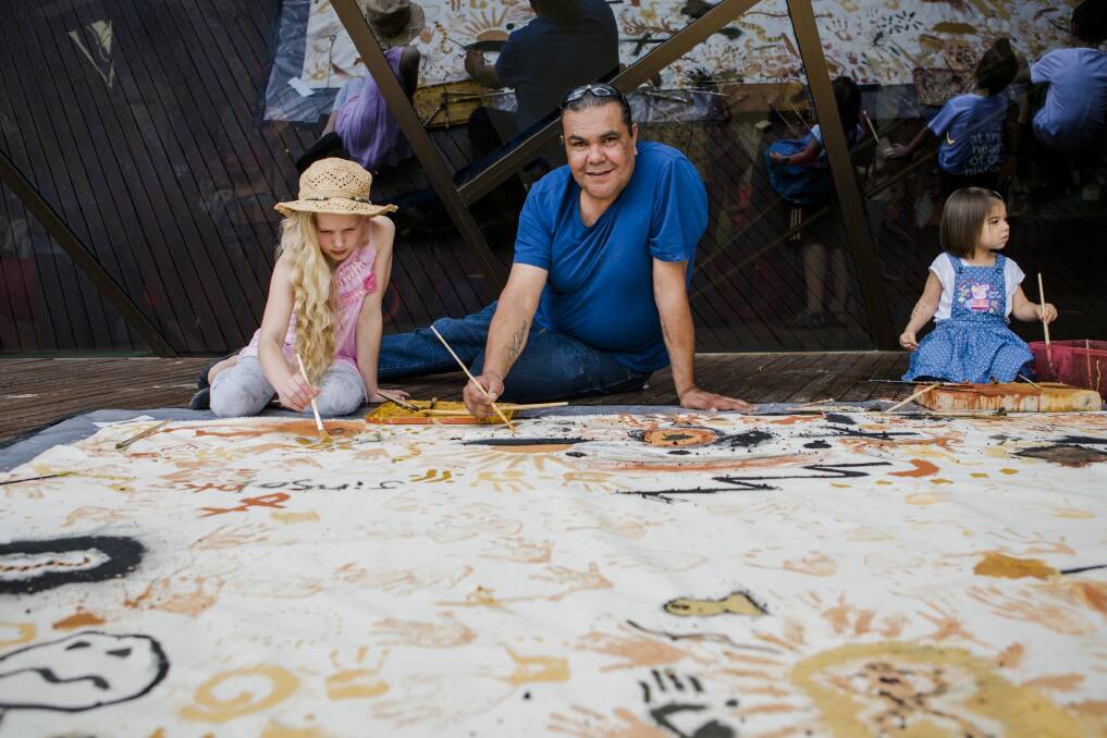 Adrian Brown, a Ngunnawal Country Ranger in the ACT Parks and Conservation Service, helps Paige von Berger, of Ainslie, with the floor mural at the National Museum's Australia Day festival. Photo: Jamila Toderas