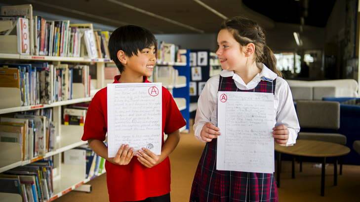 Year 4 students, Toby McCormack, from Chapman PS, and Keira Barrack from Harrison School hold their A graded work. Photo: Rohan Thomson