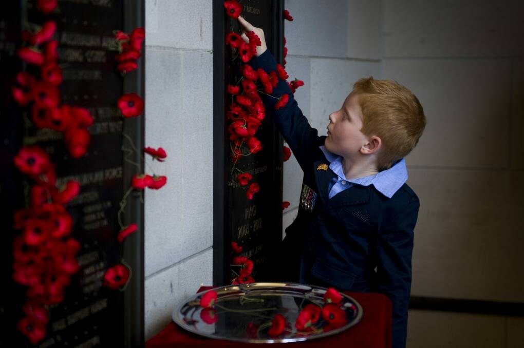 Tribute: Alex Hopkins lays a poppy next to his dad's name at the Australian War Memorial on Remembrance Day. Mathew Hopkins died in Afghanistan in 2009. Photo: Jay Cronan
