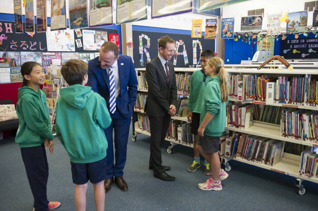  Andrew Barr, left, and Shane Rattenbury meet students at Kaleen Primary on Monday, where they announced plans to phase out paper forms and notes in schools. Photo: Jay Cronan