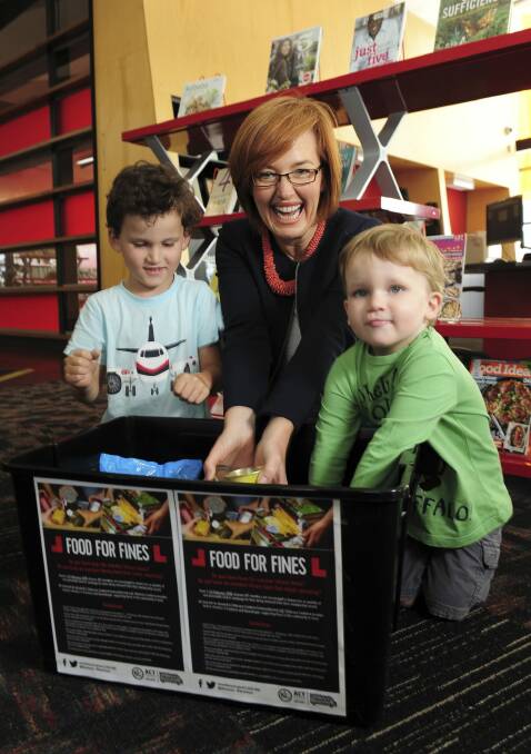Minister for Municipal Services Meegan Fitzharris at the Gungahlin Library. Book fees are being waived in return for food donations. Helping her are Eaden Chapman, 5, left, and Connor Chapman, 3, both of O'Connor. Photo: Graham Tidy