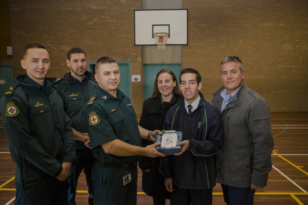 From left, call taker Matt Davis, and paramedics Sam Biddington and Peter Fraser are presented with a new defibrillator by Thomas Rowsell and his parents, Cheryl and Daniel. Photo: Jamila Toderas