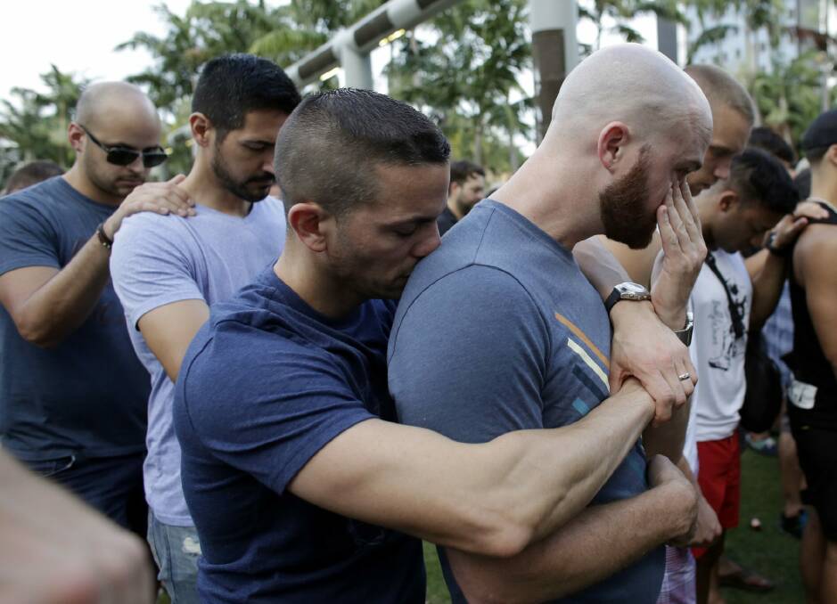 Caleb McGrew, 36, right, wipes tears as he stands with his partner Yosniel Delgado Giniebra, 37, centre, during a vigil in memory of the victims of the Orlando mass shooting,  Photo: AP