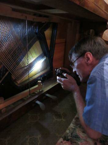 Chris Leslie makes a preliminary assessment of a now-restored piano. Photo: Jennifer Gall