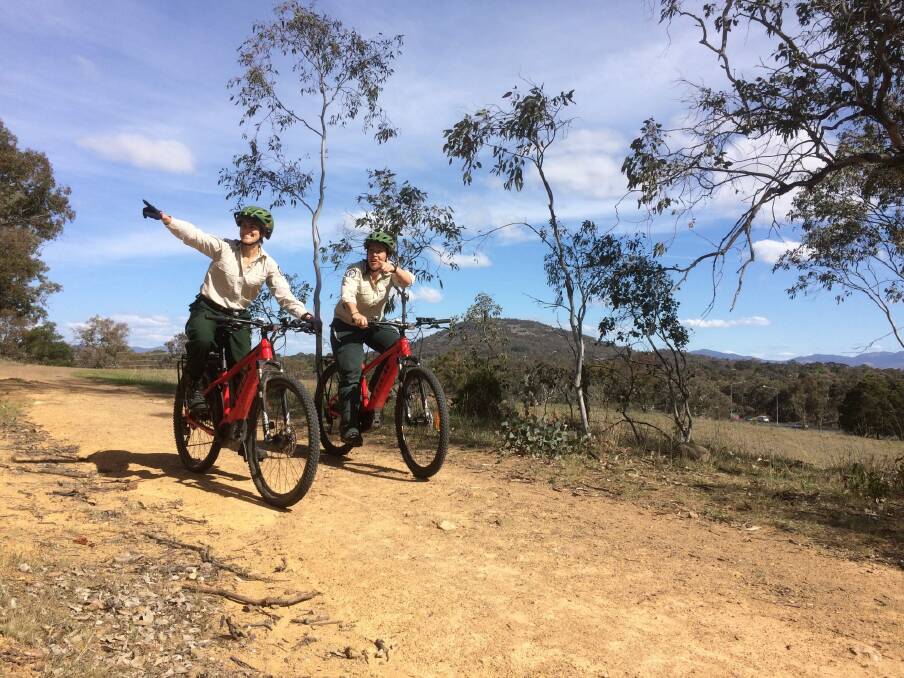ACT Parks and Conservation volunteer programs manager Alison McLeod and visitor experience manager Jasmine Foxlee riding through Canberra's nature parks on electric mountain bikes. Photo: Supplied
