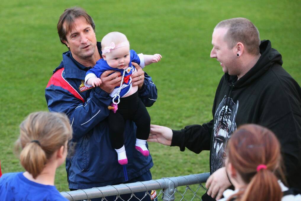 Bulldogs head coach Luke Beveridge poses with a baby during a training session at Whitten Oval on Tuesday. Photo: Getty Images