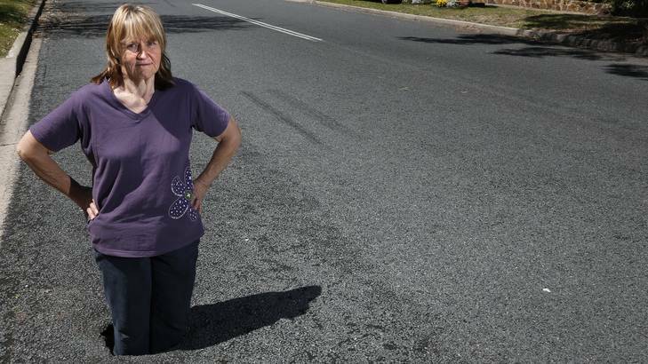 Renate Williams from Rivett standing in a hole that appeared in the road opposite her home, she sees it as a hazard to motorists and cyclists. Photo: Jeffrey Chan