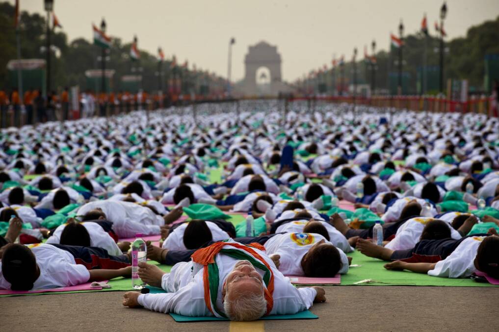 Indian Prime Minister Narednra Modi, center front, lies down on a mat as he performs yoga along with thousands of Indians on Rajpath, in New Delhi, India, Sunday, June 21, 2015. Millions of yoga enthusiasts are bending their bodies in complex postures across India as they take part in a mass yoga program to mark the first International Yoga Day. Photo: AP