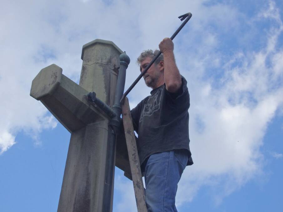 A photo of a Catholic Worker movement member removing the sword from the Cross of Sacrifice on Ash Wednesday in 2017. Photo: Supplied